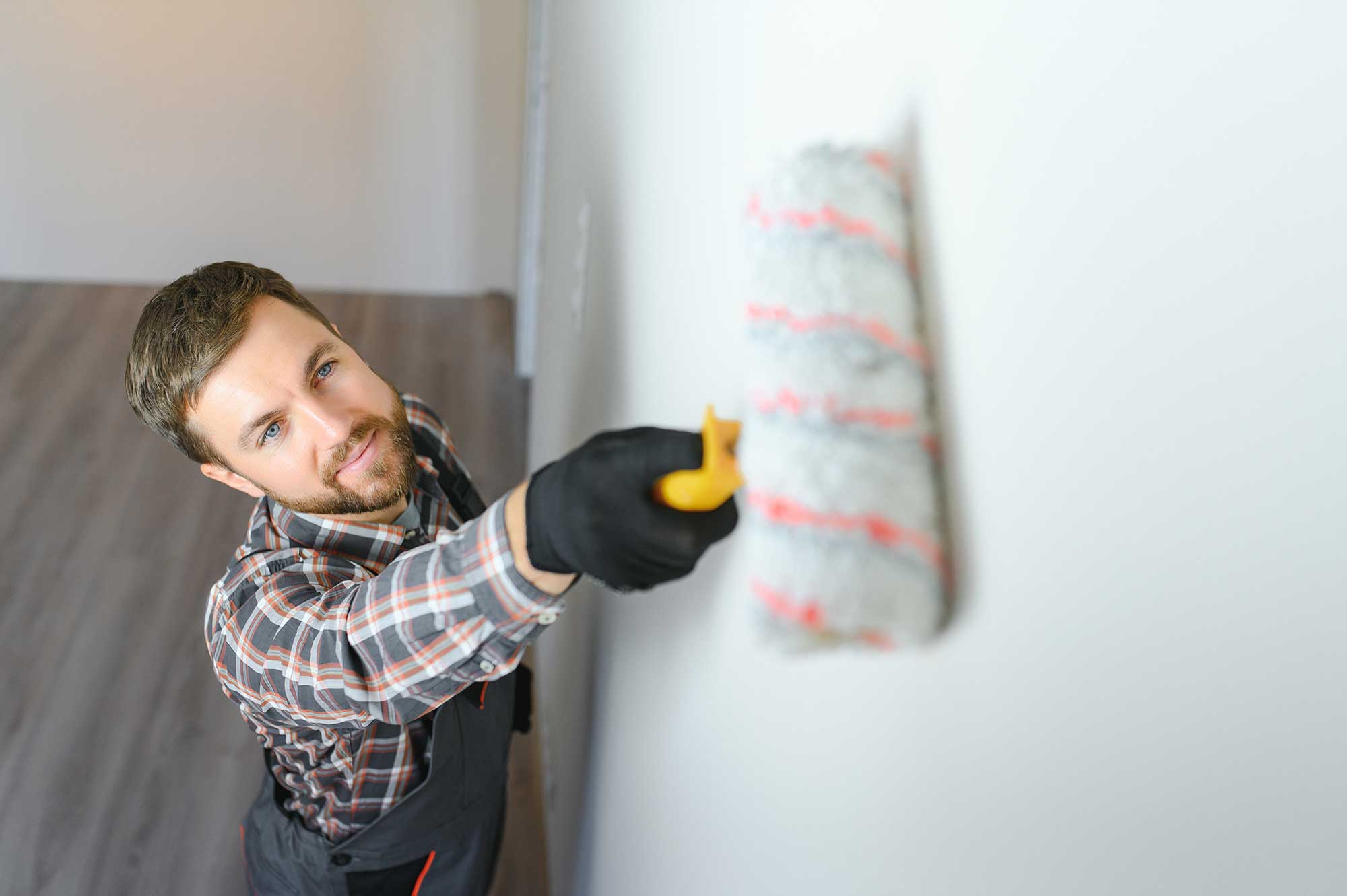 Skilled painter using a roller to apply paint on an interior wall during a residential project.